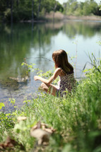 Girl sitting beside pond