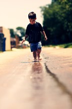 Young boy playing in water with bare feet