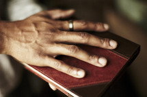 A man placing his hand on the front cover of a Bible