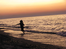 a girl child running on a beach of Lake Michigan 