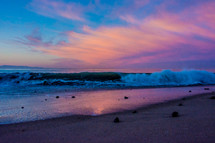 waves crashing onto a shore at sunset 
