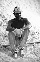 A black Haitian man sits after working hard
