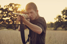 A young man aiming a rifle.