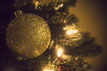gold glitter ball Christmas ornament on a Christmas tree