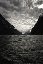A New Zealand bay surrounded by mountains and storm water with dark clouds