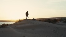 Backpacker Man On A Sand Dune At Sunset