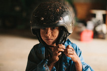 A muddy boy wearing a helmet
