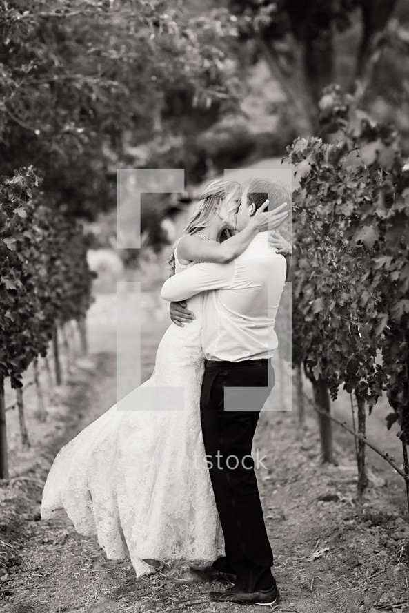 Bride and groom kissing outdoors in a vineyard embrace, love romance wedding napa valley