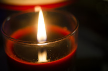 Lit, red votive candle.