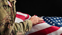 Military man in Uniform touching USA flag with his hand