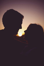 The silhouette of a couple holding each other at sunset 