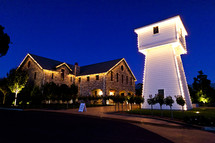 View of winery stone building and white tower at night.