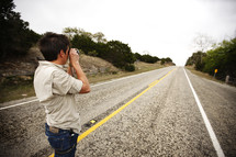 A man takes a picture looking down the highway