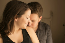 man kissing a woman's shoulder