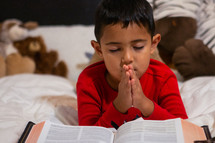 child reading a Bible in bed