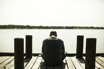 A man sitting and praying on a dock