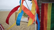 rainbow kites and flags blowing on a beach house porch 