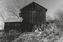A child stands in front of an old wood barn in the countryside of Pennsylvania