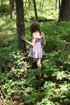child walking through overgrowth in on a forest floor