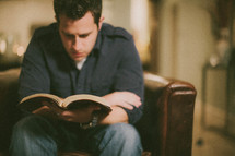 man sitting reading a Bible