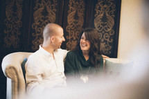 couple smiling at each other sitting on a couch