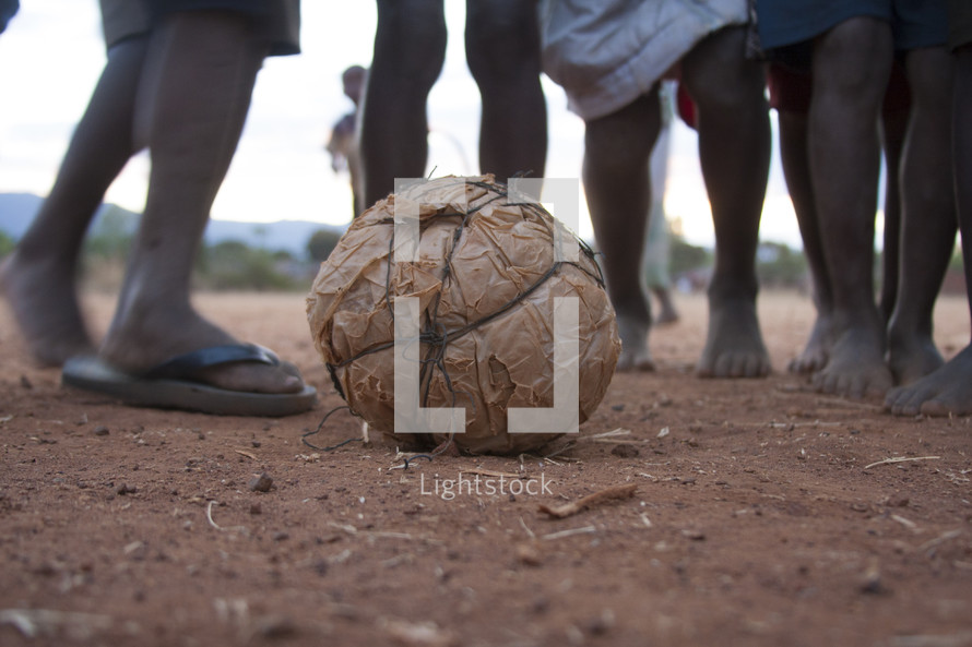 feet of children playing with a ball homemade of plastic and string