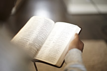 An over-the-shoulder view of a man reading a bible