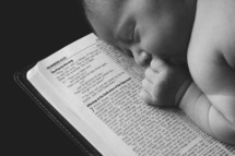 Infant sleeping on top of an open bible