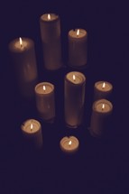 A collection of lit candles isolated on black