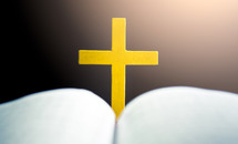 Open holy bible with yellow cross in the middle