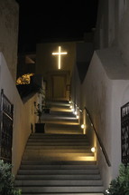 illuminated cross at the top of a stairway 