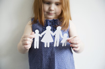 A little girl holds a paper cutout of a family.