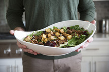 a man holding a large salad bowl 
