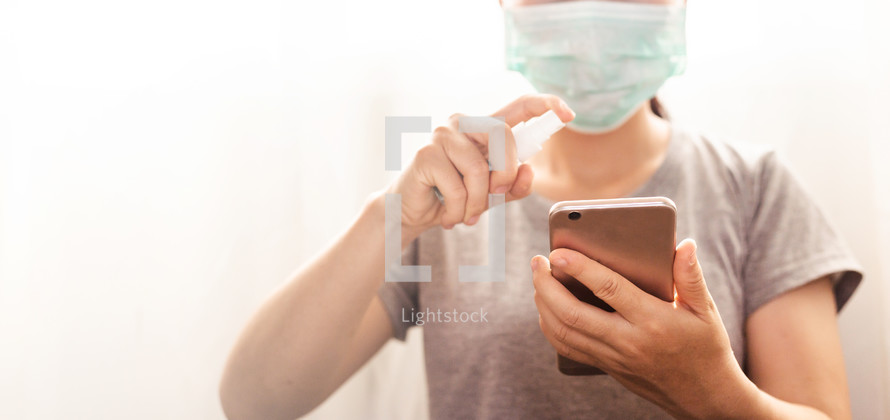 woman sanitizing her phone 