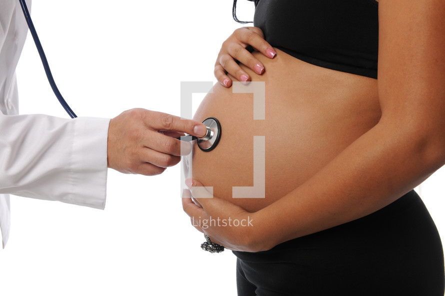 A doctor pressing a stethoscope to a pregnant woman's stomach.