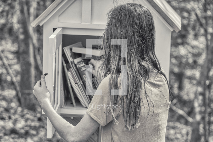 girl visiting a little library in a neighborhood 