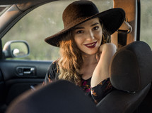 a woman in a hat sitting in car 