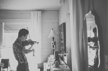 a teenage boy playing a fiddle in a mirror 