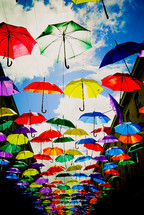 rainbow colored umbrellas over a walkway 