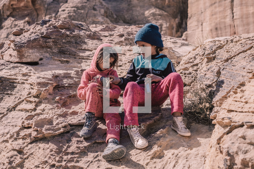 little girls sitting in a desert 