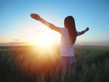 woman standing in a field with outstretched arms 