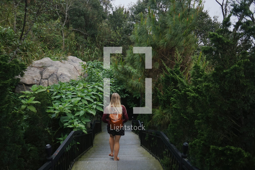 a woman walking down steps into a jungle 