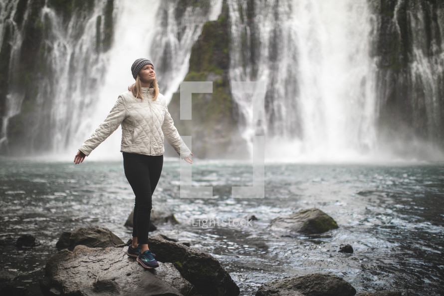 woman standing outdoors with a waterfall in the background 