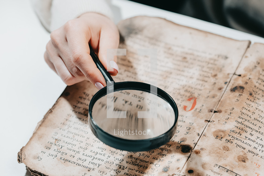 Historian scientist reading antique book with magnifying glass. Translation of religious literature. Manuscript with ancient writings. Treasures of the past. Museum piece.