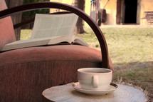 tea cup and open Bible in a chair outdoors 