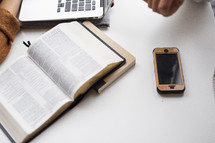 Bible, laptop, journal, and cellphone on a white table 