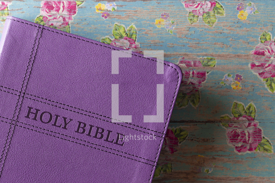 purple Bible on a floral background 