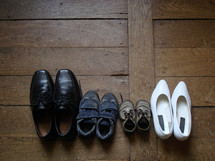 Family's shoes lined up on a wood floor. 