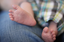 Newborn baby boy feet, sitting on mom's lap.