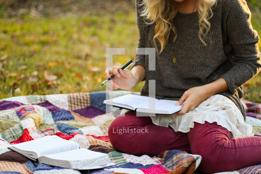 woman sitting on a blanket reading a Bible 